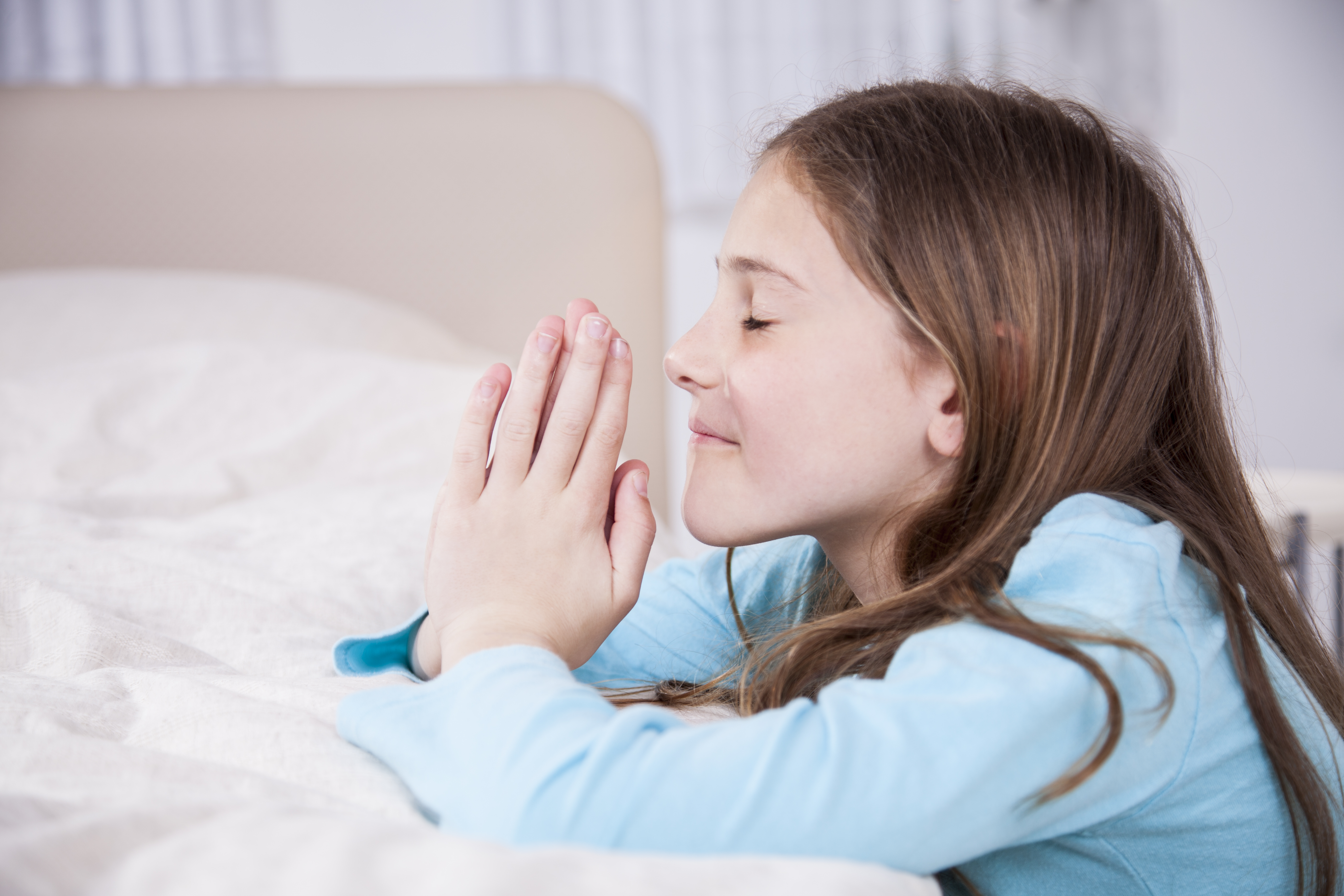 Praying girl at the side of her bed