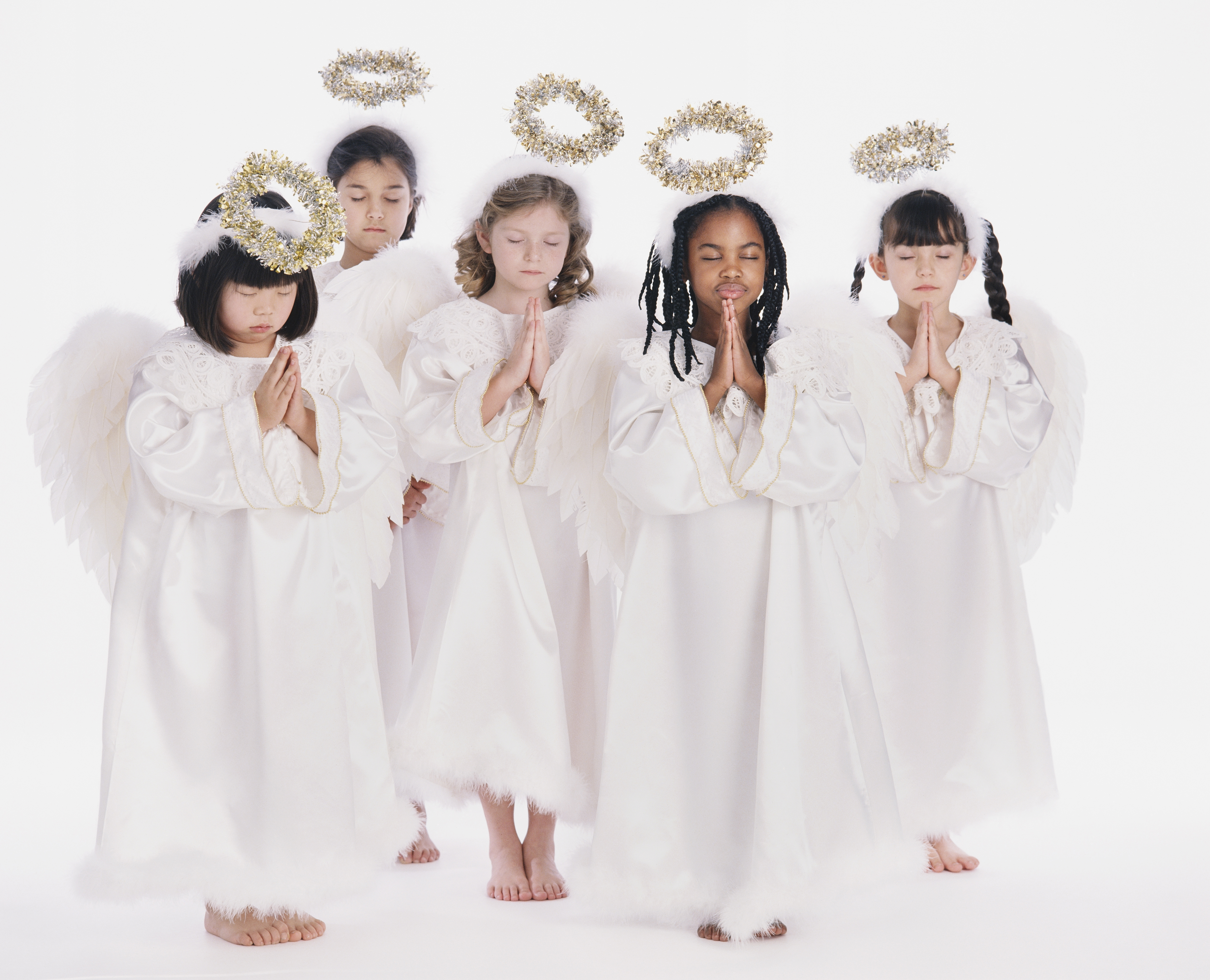 Diverse group of girls wearing angel costumes praying